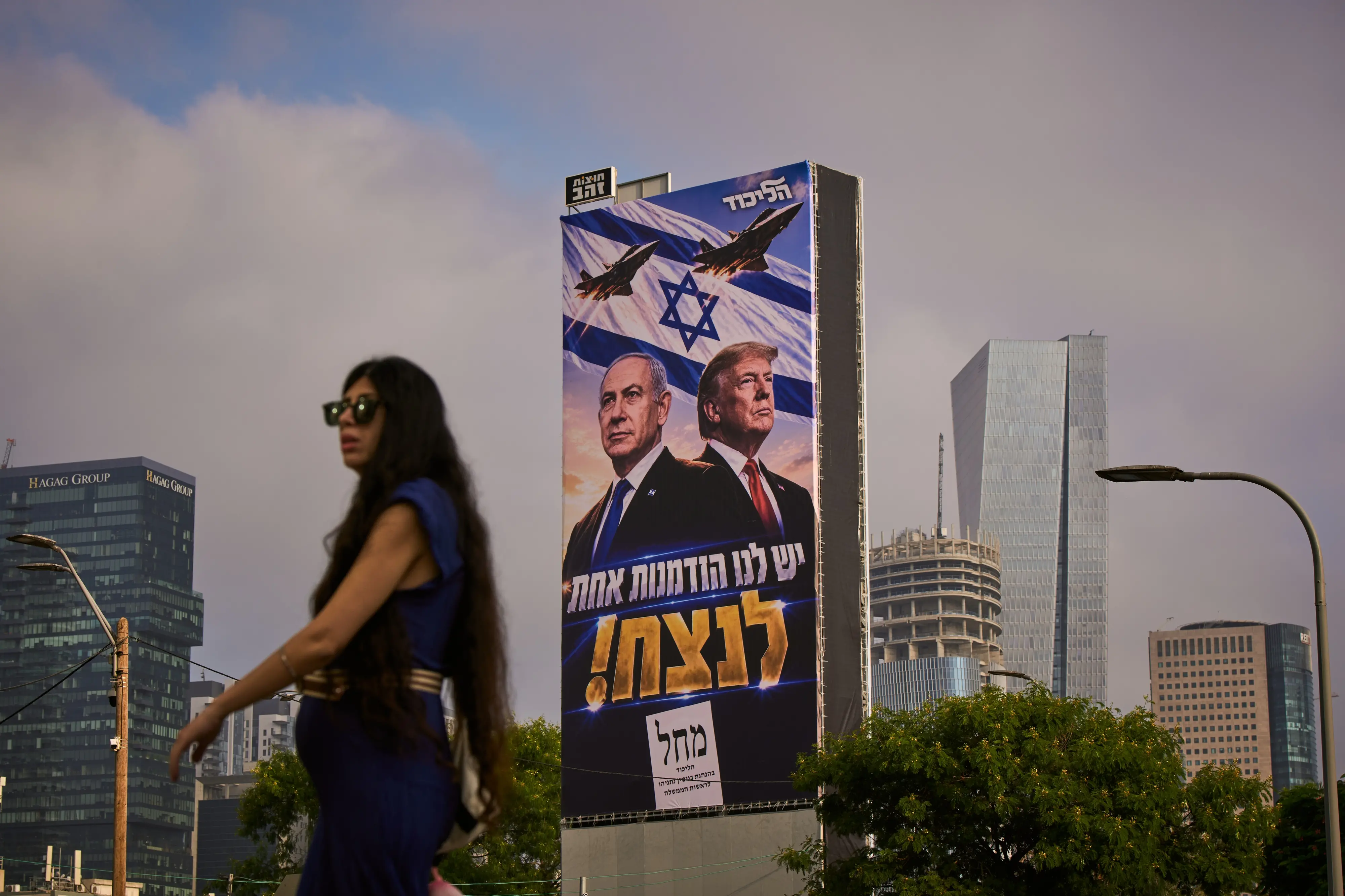 A woman walks past a Likud Party campaign billboard featuring US President Donald Trump and Israeli Prime Minister Benjamin Netanyahu, with a Hebrew message reading, "We have one opportunity to win", in Tel Aviv  |  Photo: AP/PTI